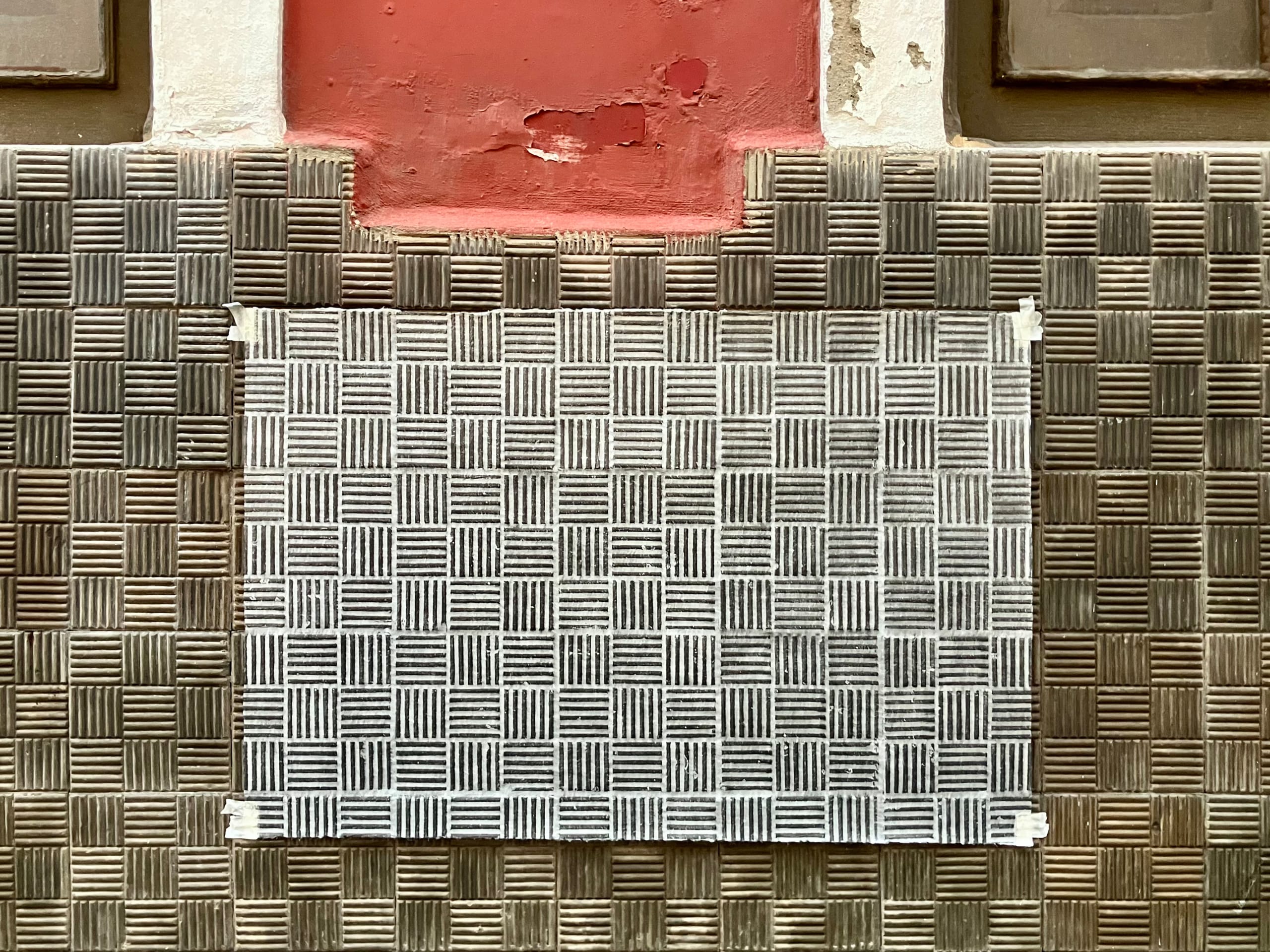 Papel japonés fijado sobre un zócalo de piezas estriadas, con un frottage en grafito que reproduce su patrón de cuadrados y líneas alternas.